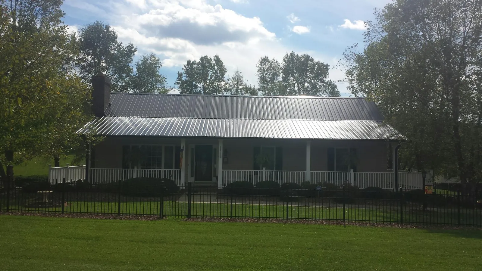 Gray metal roof on a brick ranch with a full width front porch — Gutter Guard Installation work by our crew in Whitesville